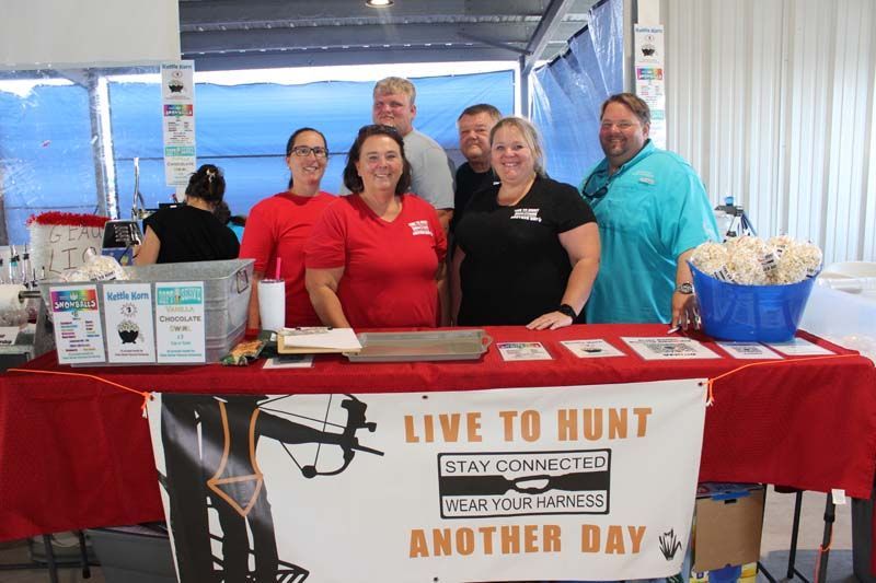 A group of people standing around a table with a sign that says live to hunt another day.