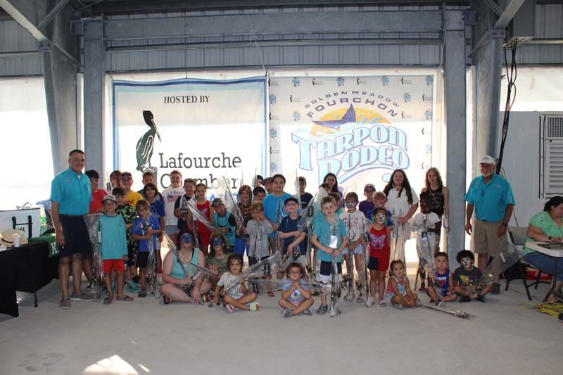 A group of children are posing for a picture in front of a sign.