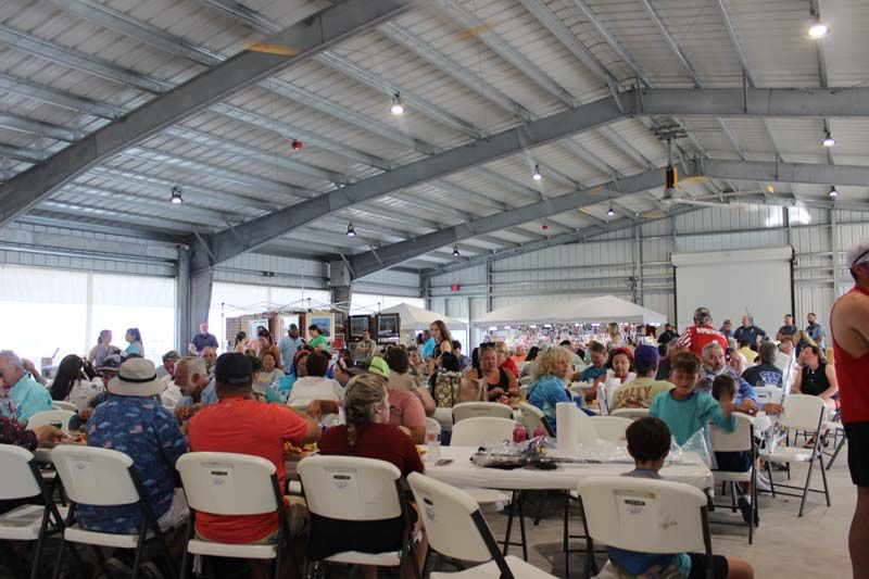 A large group of people are sitting at tables in a large building.