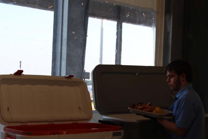 A man is holding a tray of food in front of a window