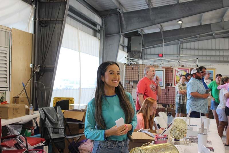 A woman in a blue shirt is standing in a room with a group of people.