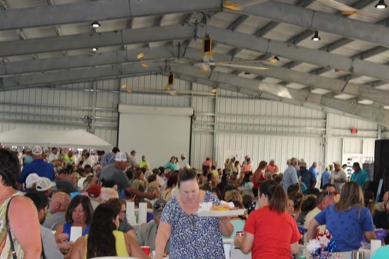 A woman is serving food to a crowd of people in a large room.