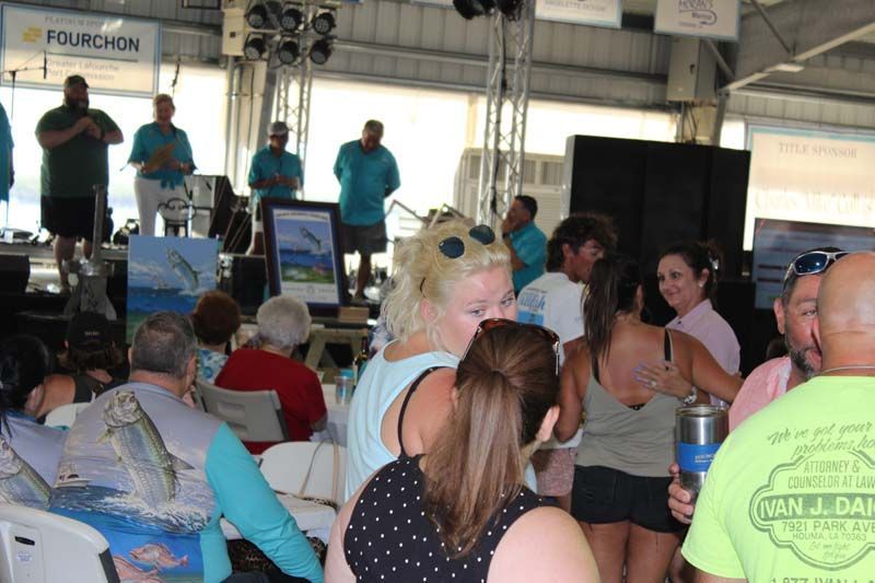 A group of people are gathered in a room with a sign that says fourchon on it