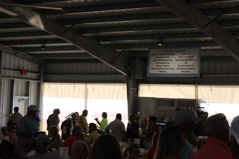 A large group of people are gathered in a room with a menu on the wall above them
