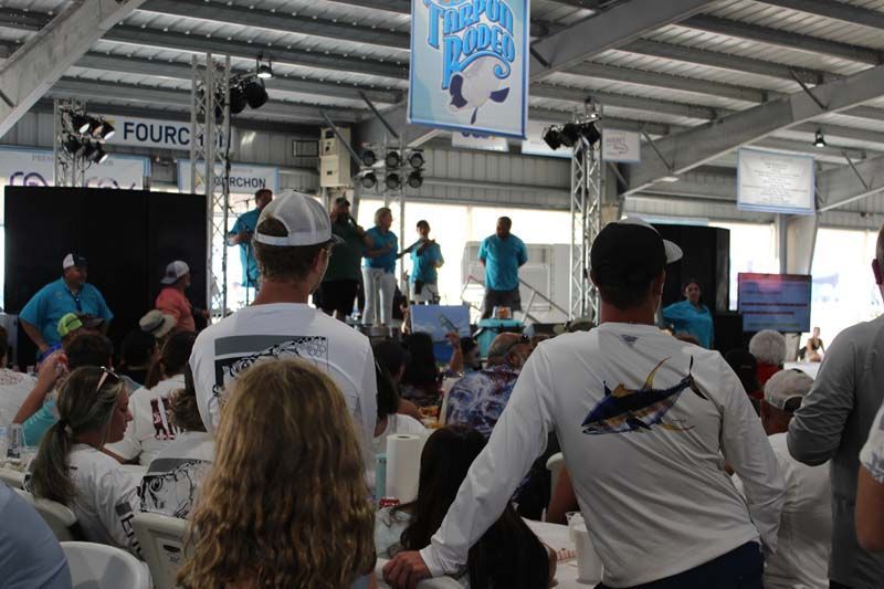 A group of people are gathered in a room with a sign that says ' fourth place ' on it