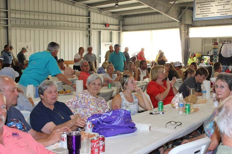 A large group of people are sitting at long tables eating and drinking.