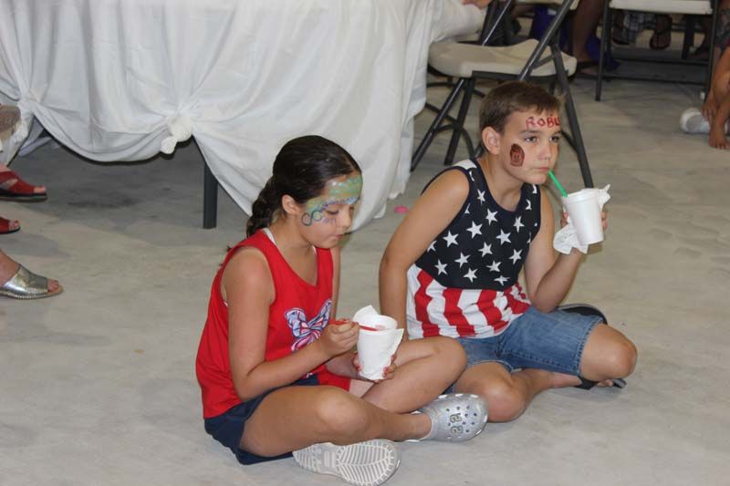 A boy and a girl are sitting on the floor eating ice cream