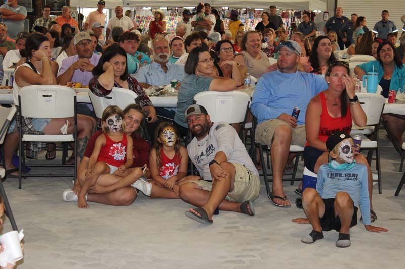 A large group of people are sitting in chairs at a party.