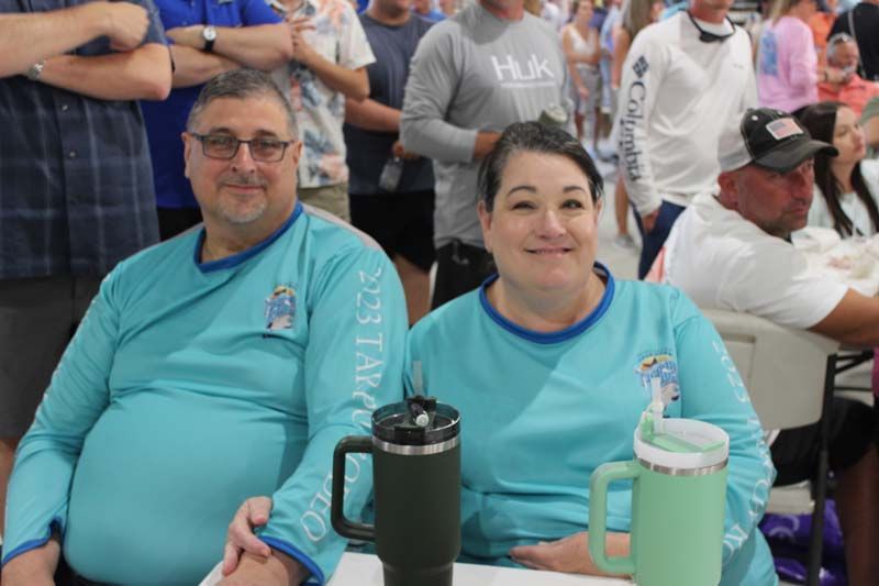 A man and a woman are sitting at a table in front of a crowd of people.