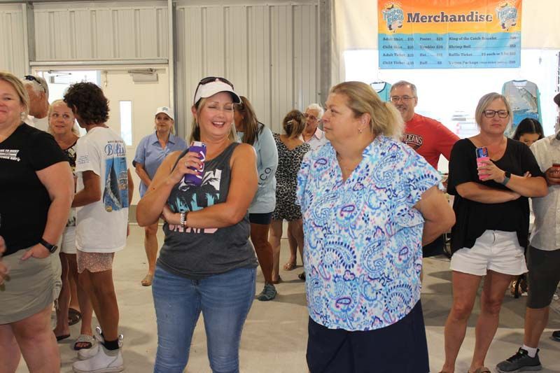 A group of people are standing in a room with a sign that says merchandise.