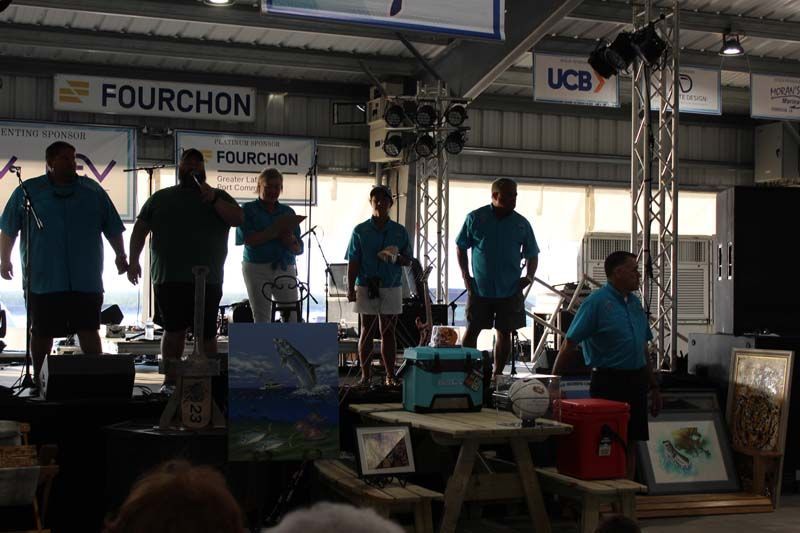 A group of men are standing on a stage in front of a sign that says fourchon