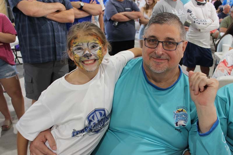 A man and a girl with face paint are posing for a picture.