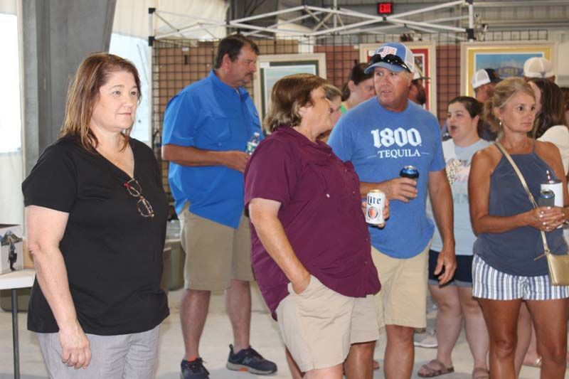 A group of people are standing in a room and one of them is wearing a 1800 tequila shirt.