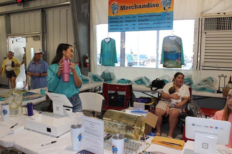A woman is standing in front of a table with a sign that says merchandise.