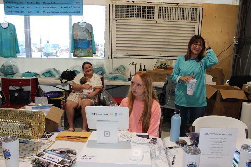 A woman is holding a baby while sitting at a desk in front of a computer.