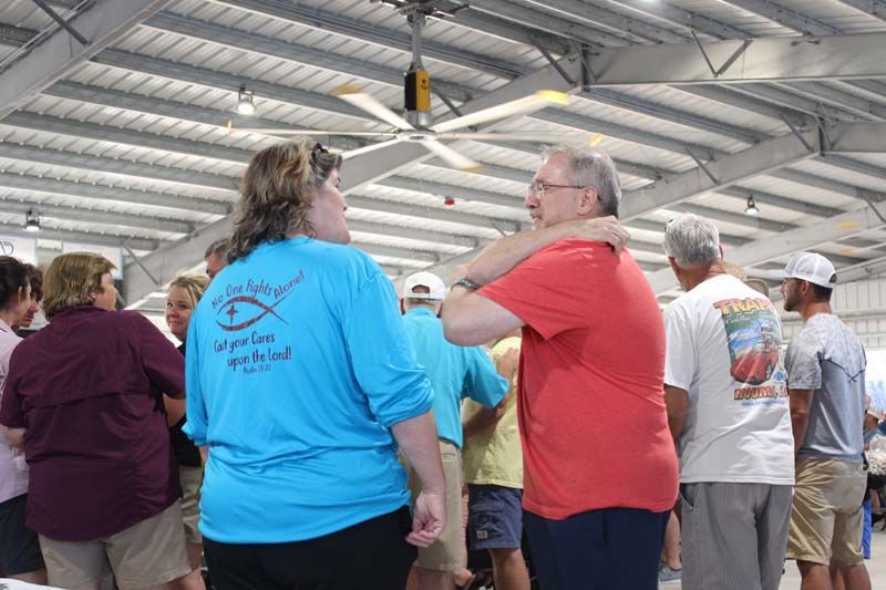 A group of people are standing in a room with a ceiling fan.