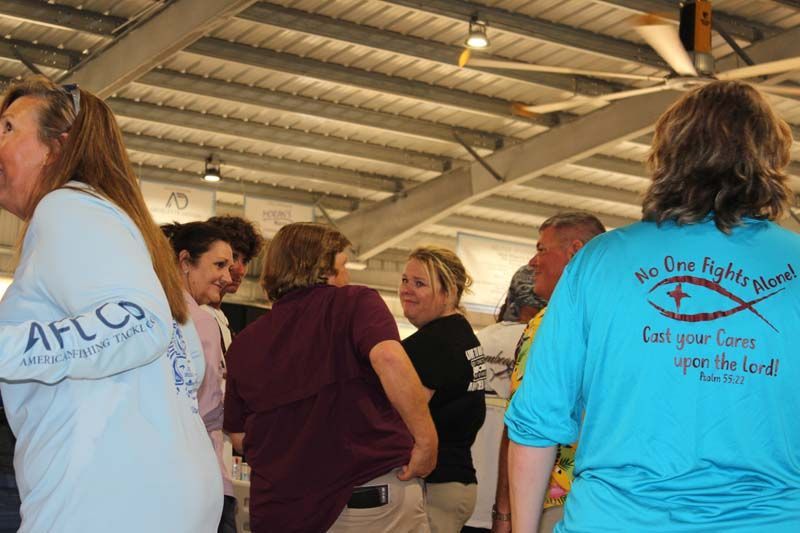 A group of people are standing in a room wearing shirts that say no one fights alone.