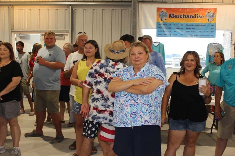 A group of people are standing in front of a sign that says merchandise.