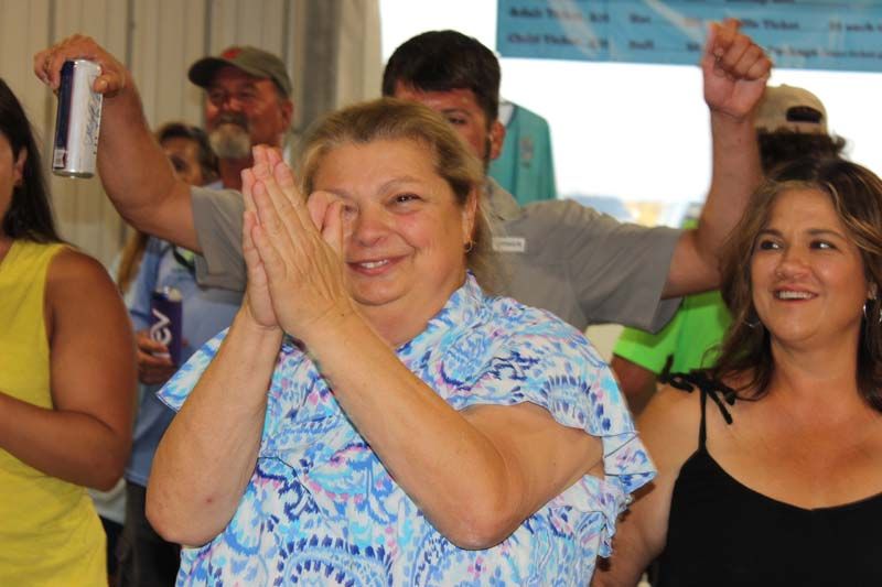 A woman in a blue and white shirt is clapping her hands