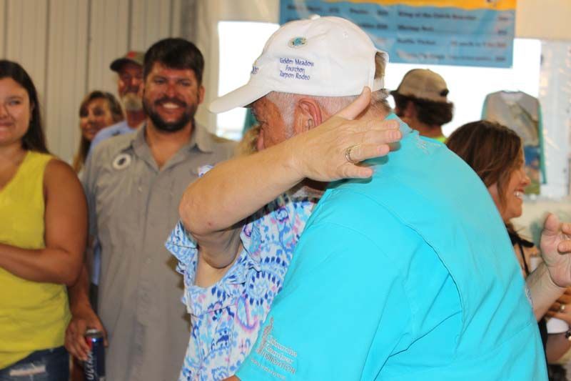 A man in a white hat is hugging a woman in a blue shirt.