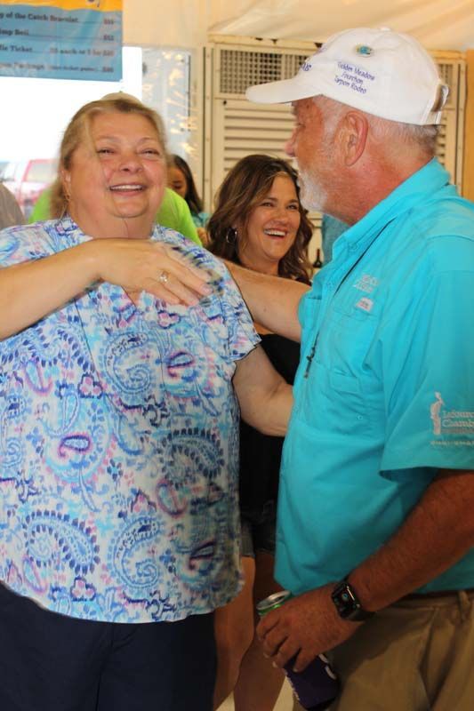 A man in a white hat is hugging a woman in a blue shirt.