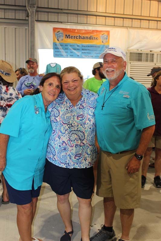 Three people posing for a picture in front of a sign that says merchandise