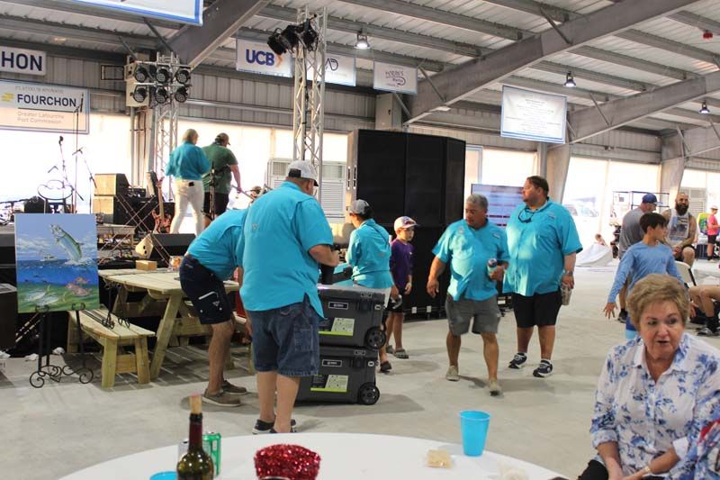 A group of people in blue shirts are standing around a table.