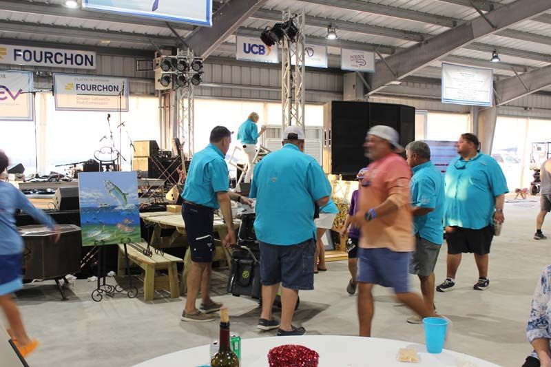 A group of people in blue shirts are standing around a table.