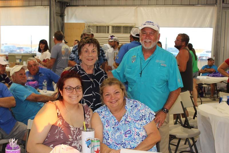 A group of people are posing for a picture while sitting at tables.