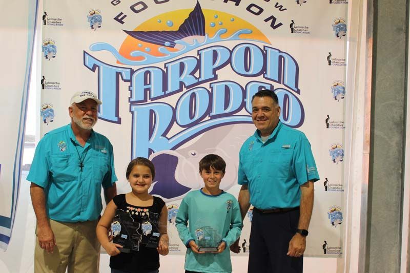 A group of people standing in front of a tarpon rodeo sign