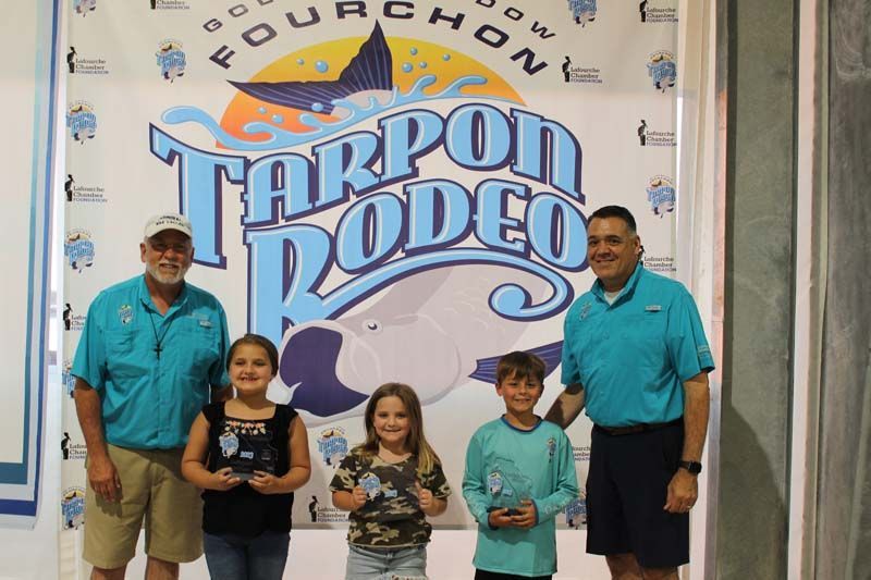A group of people standing in front of a tarpon rodeo sign