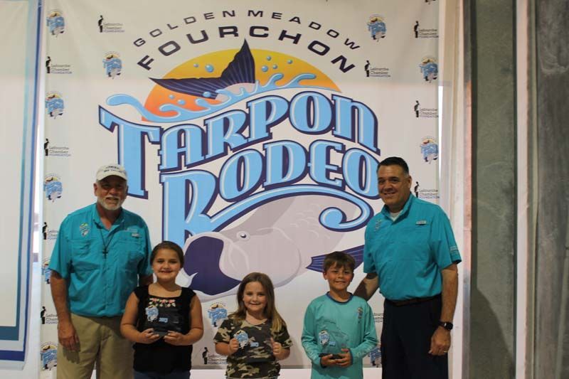 A group of people standing in front of a tarpon rodeo sign