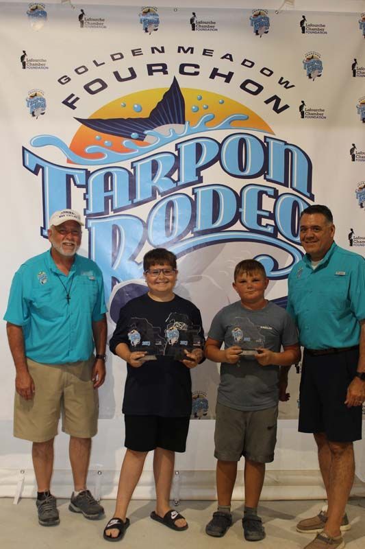 A group of people standing in front of a tarpon rodeo banner