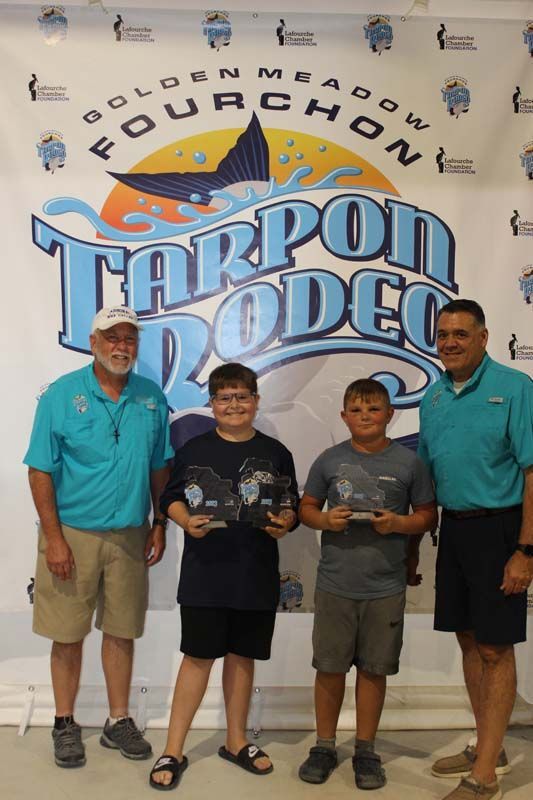 A group of people standing in front of a tarpon rodeo banner
