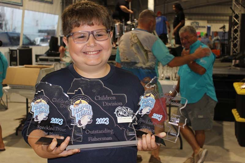 A young boy wearing glasses is holding a trophy in his hands.