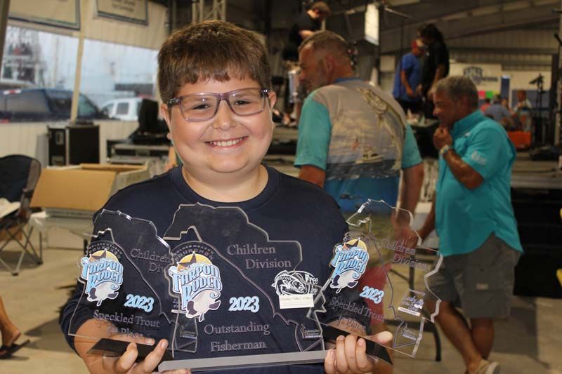 A young boy wearing glasses is holding a trophy.