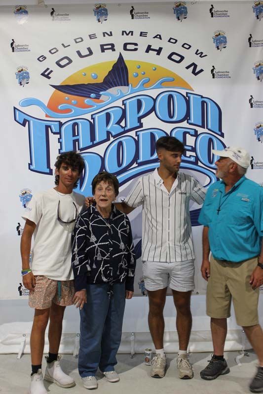 A group of people standing in front of a tarpon dodge sign
