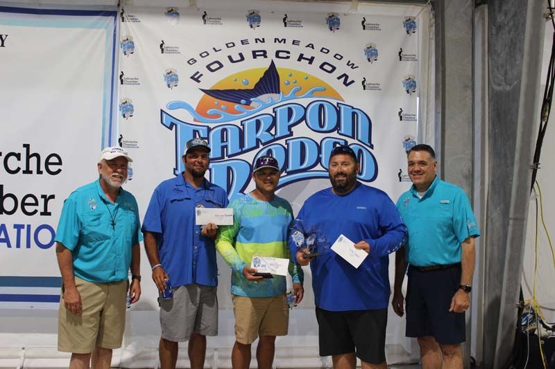 A group of men are standing in front of a banner that says tarpon dodge.