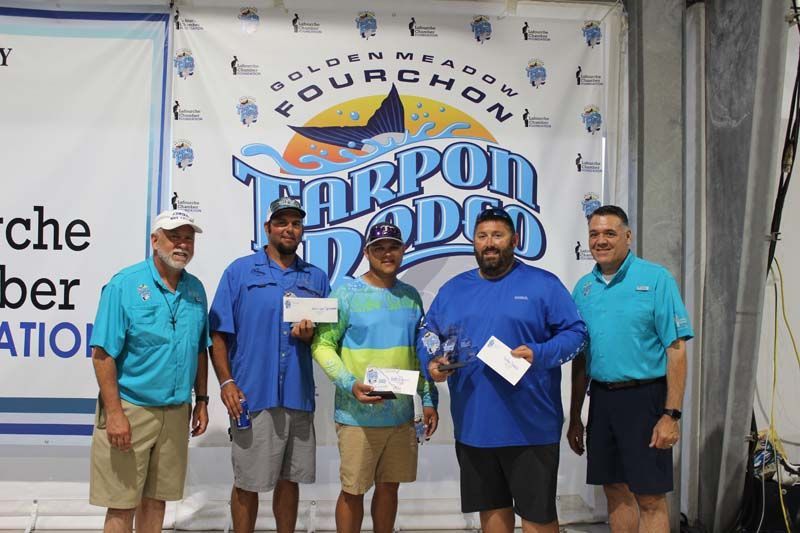 A group of men are posing for a picture in front of a banner.