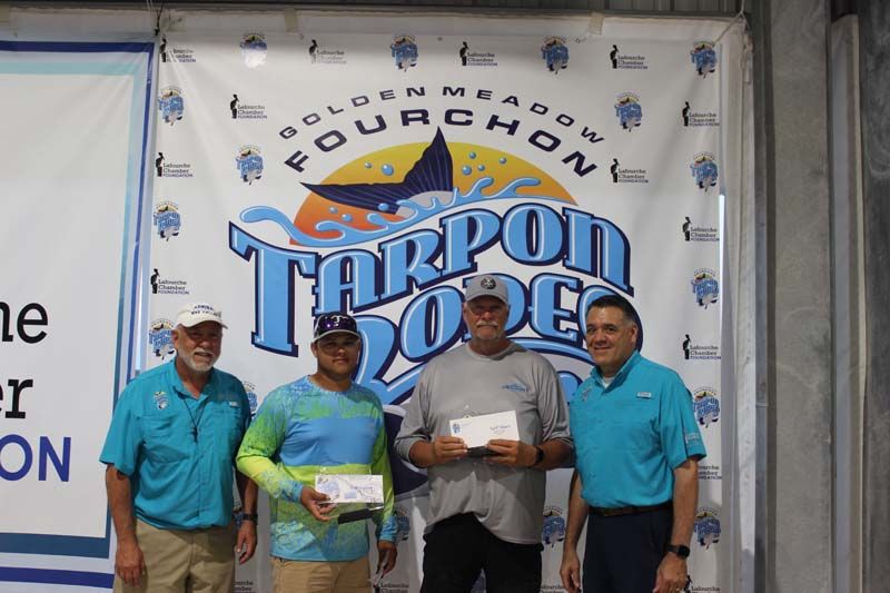 A group of men standing in front of a tarpon dope banner
