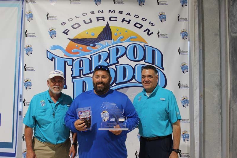 Three men standing in front of a banner that says tarpon dodge