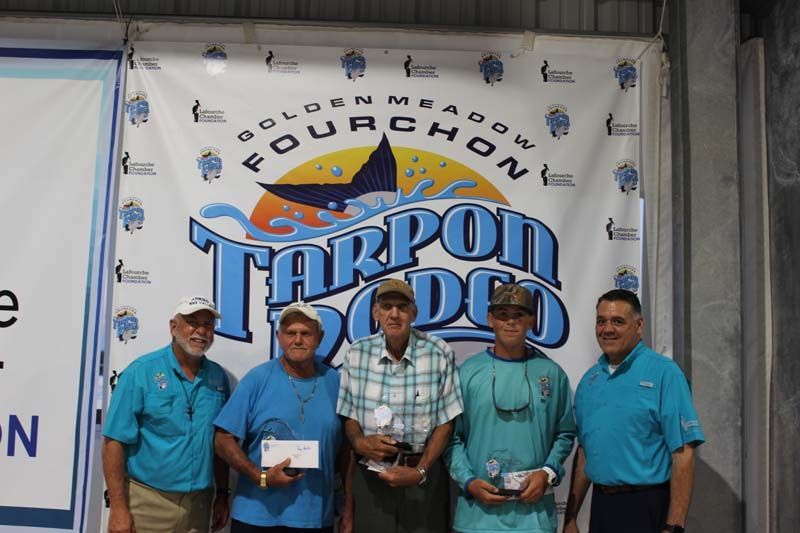 A group of men standing in front of a tarpon doo sign