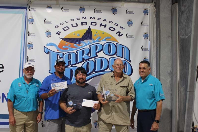A group of men standing in front of a banner that says tarpon rodeo