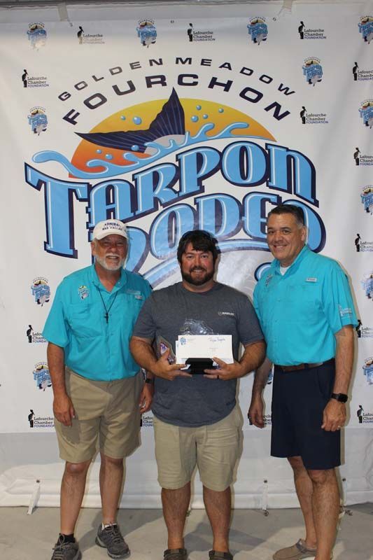 Three men standing in front of a tarpon dodge sign