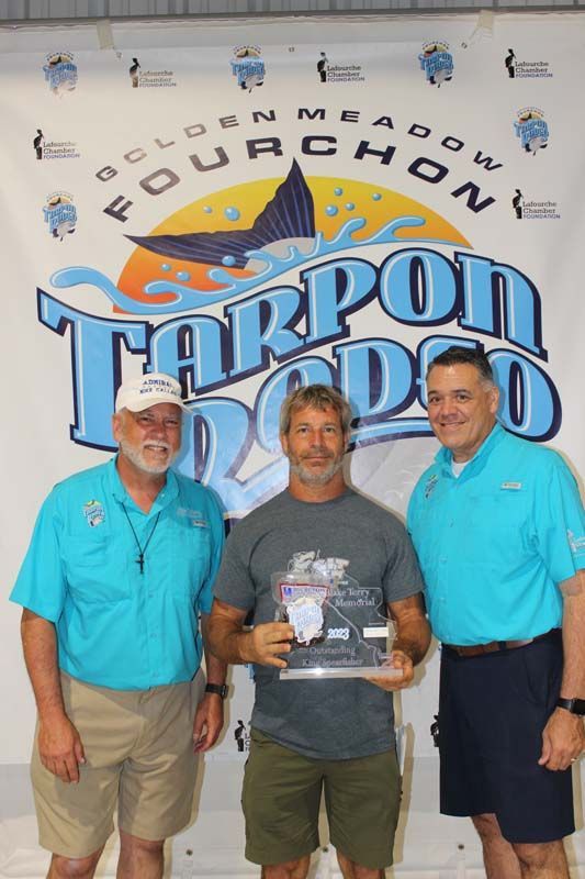 Three men standing in front of a tarpon rodeo sign