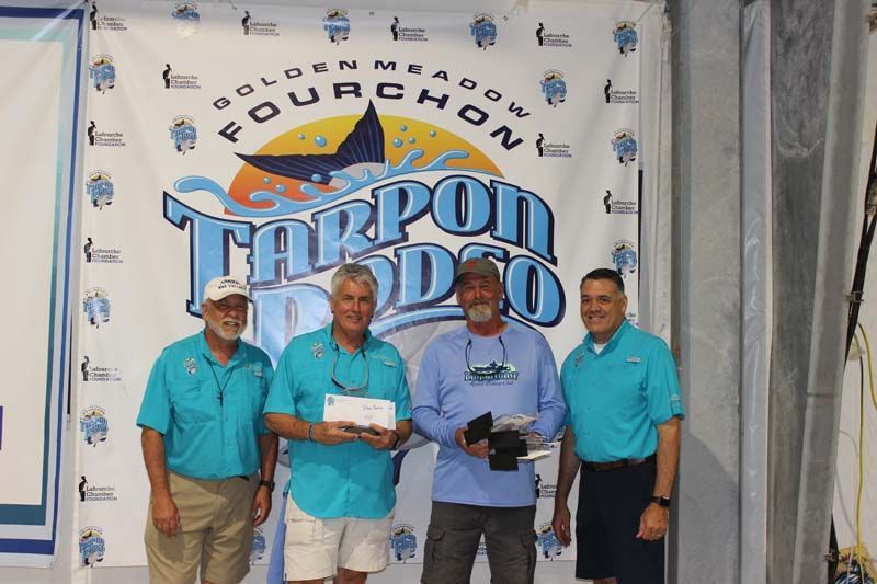 Four men are standing in front of a banner that says tarpon rodeo