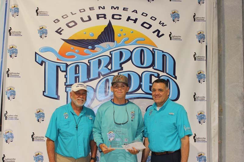 Three men standing in front of a banner that says tarpon doo