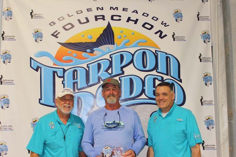 Three men standing in front of a banner that says tarpon doo