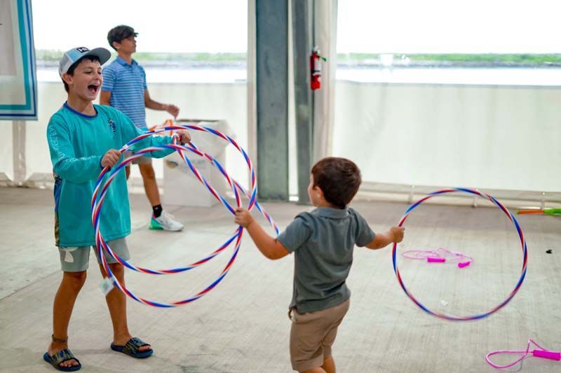 Two young boys are playing with hula hoops in a room.