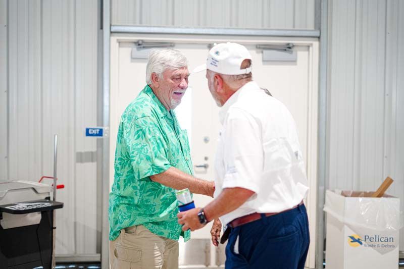 Two men are shaking hands in front of a pelican trash can